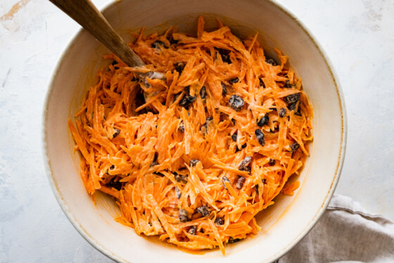 A carrot raisin salad in a large mixing bowl.