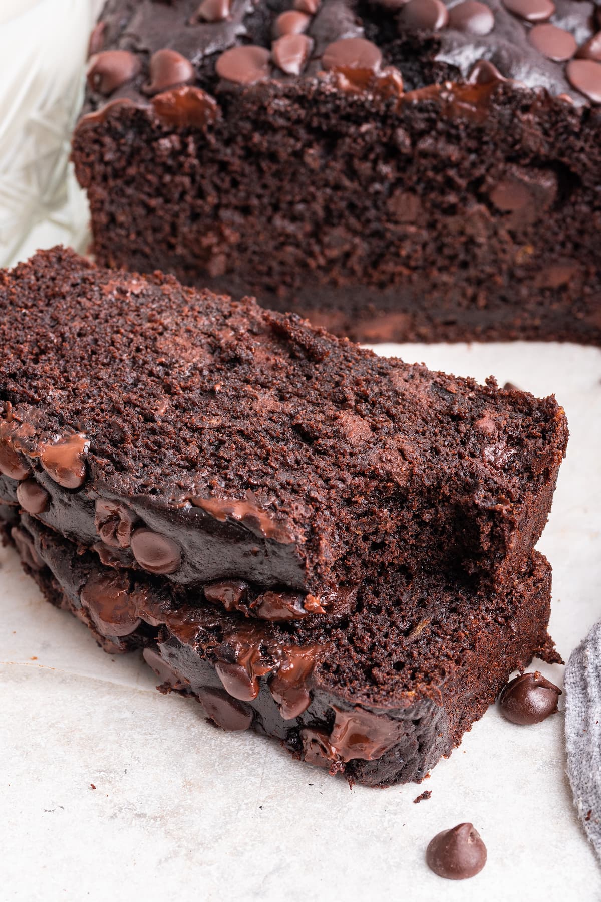 Two chocolate banana bread slices stacked on each other with a bite taken out of one.