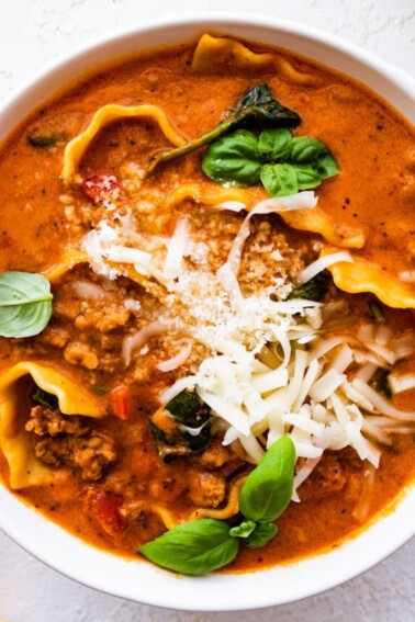 Lasagna soup in a bowl, garnished with Parmesan cheese and fresh basil.
