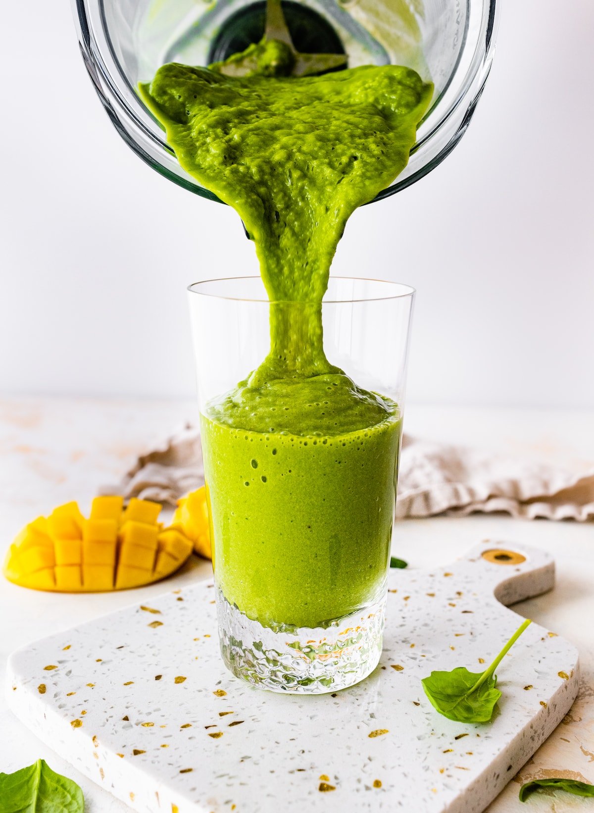 Green smoothie being poured into a glass.