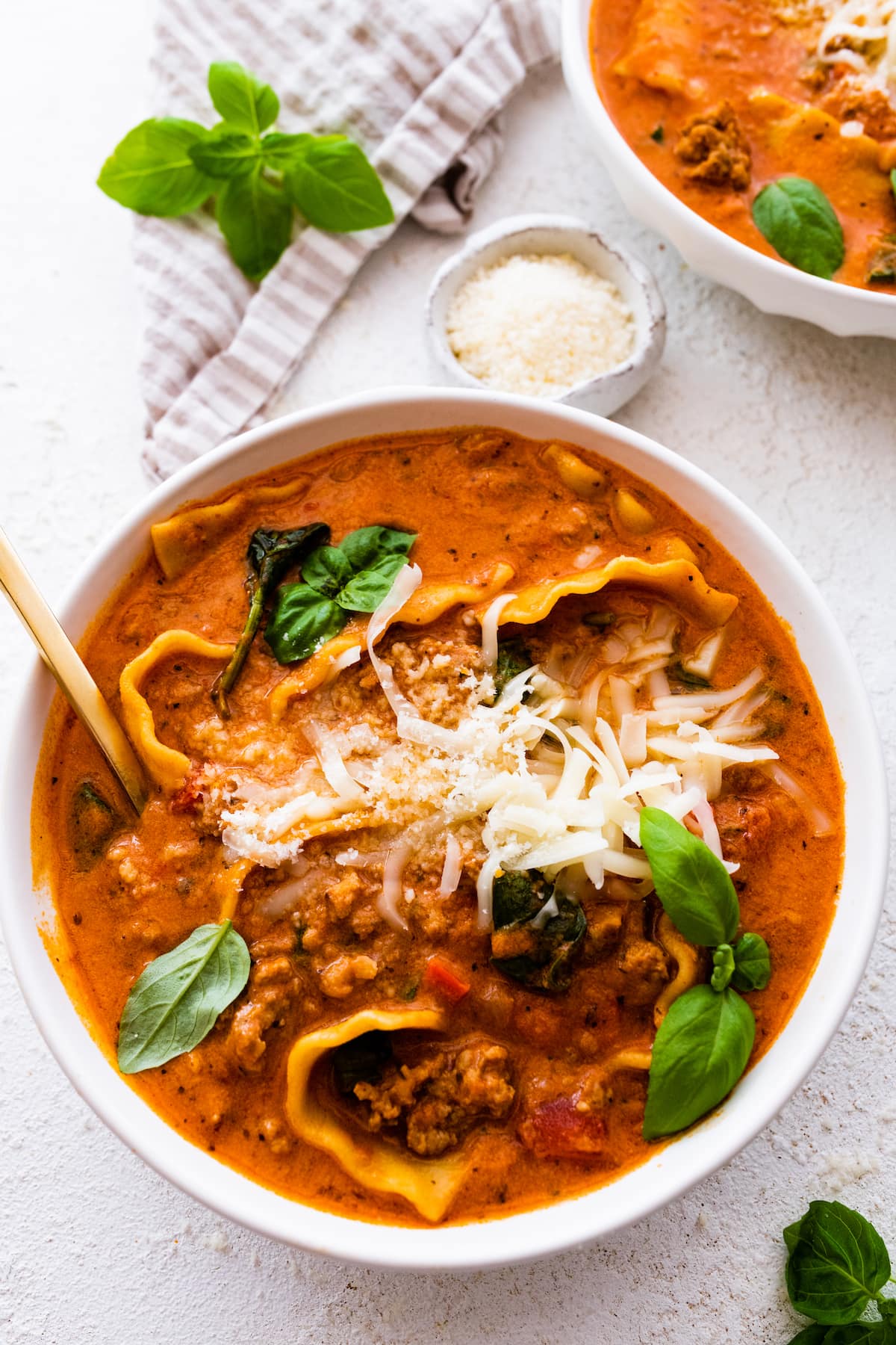 Lasagna soup in a bowl, garnished with Parmesan cheese and fresh basil.