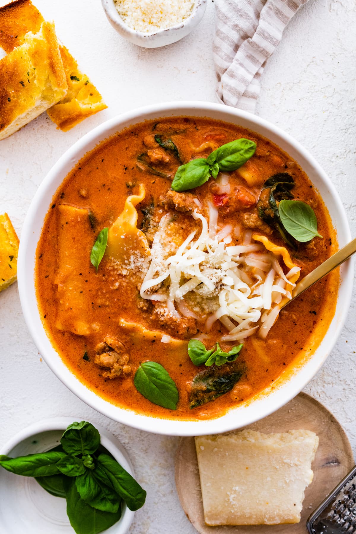 Lasagna soup in a bowl, garnished with Parmesan cheese and fresh basil.