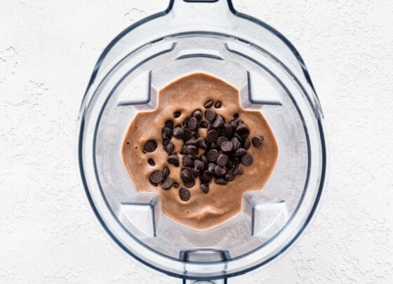 Chocolate chips added to a muddy buddy protein shake that is in a blender.