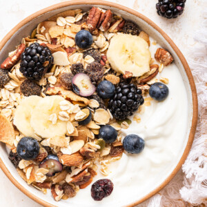 A bowl of yogurt topped with fresh berries, banana slices, and muesli.