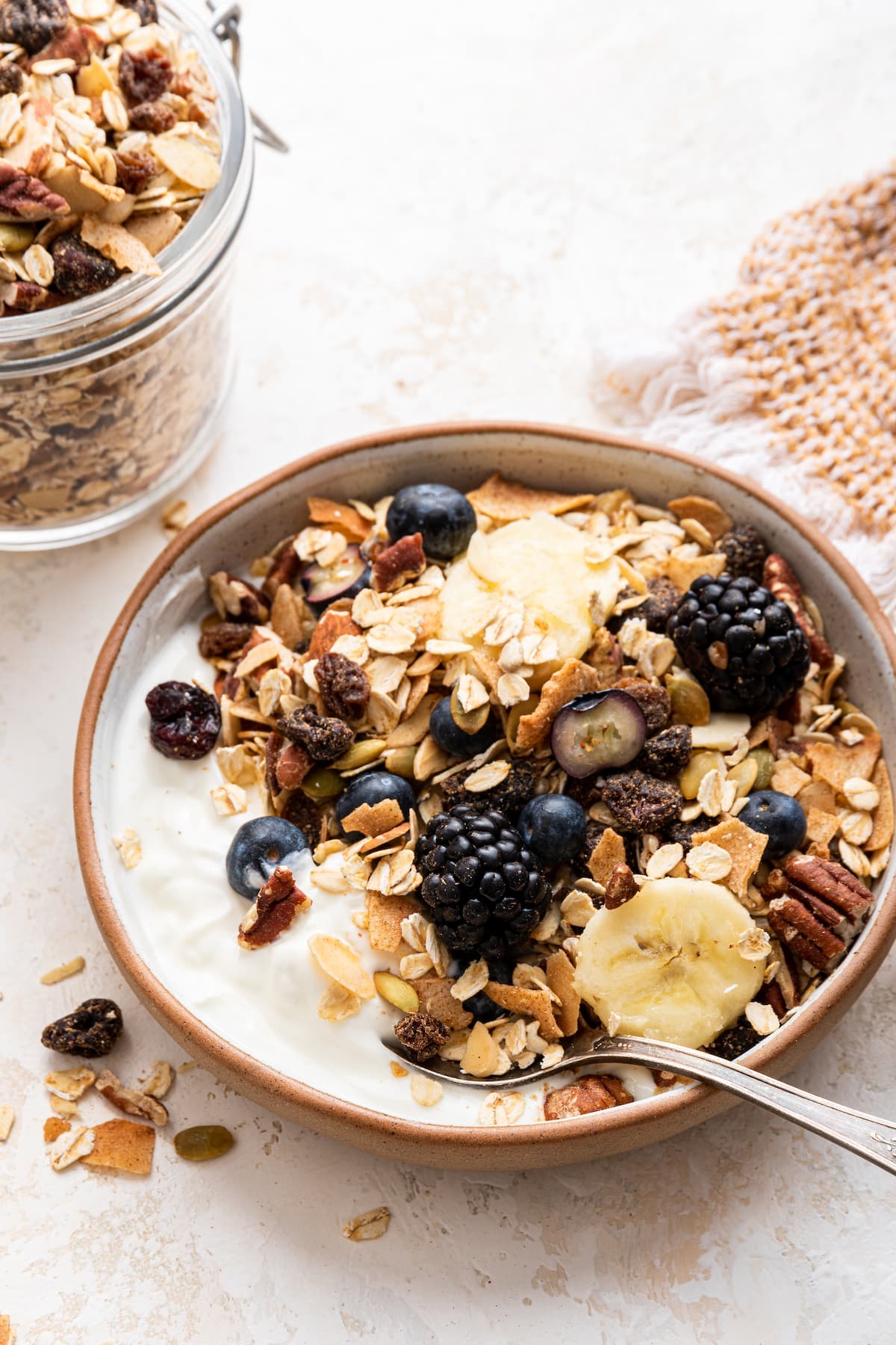 A bowl of yogurt topped with fresh berries, banana slices, and muesli.