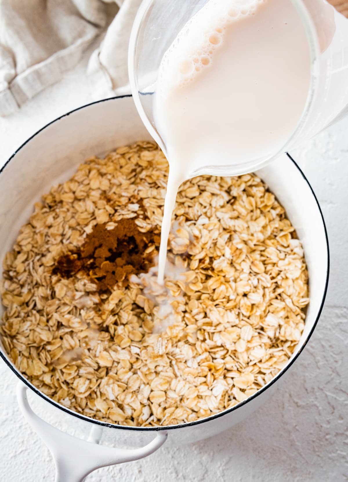 Milk being poured into a pot with rolled oats.