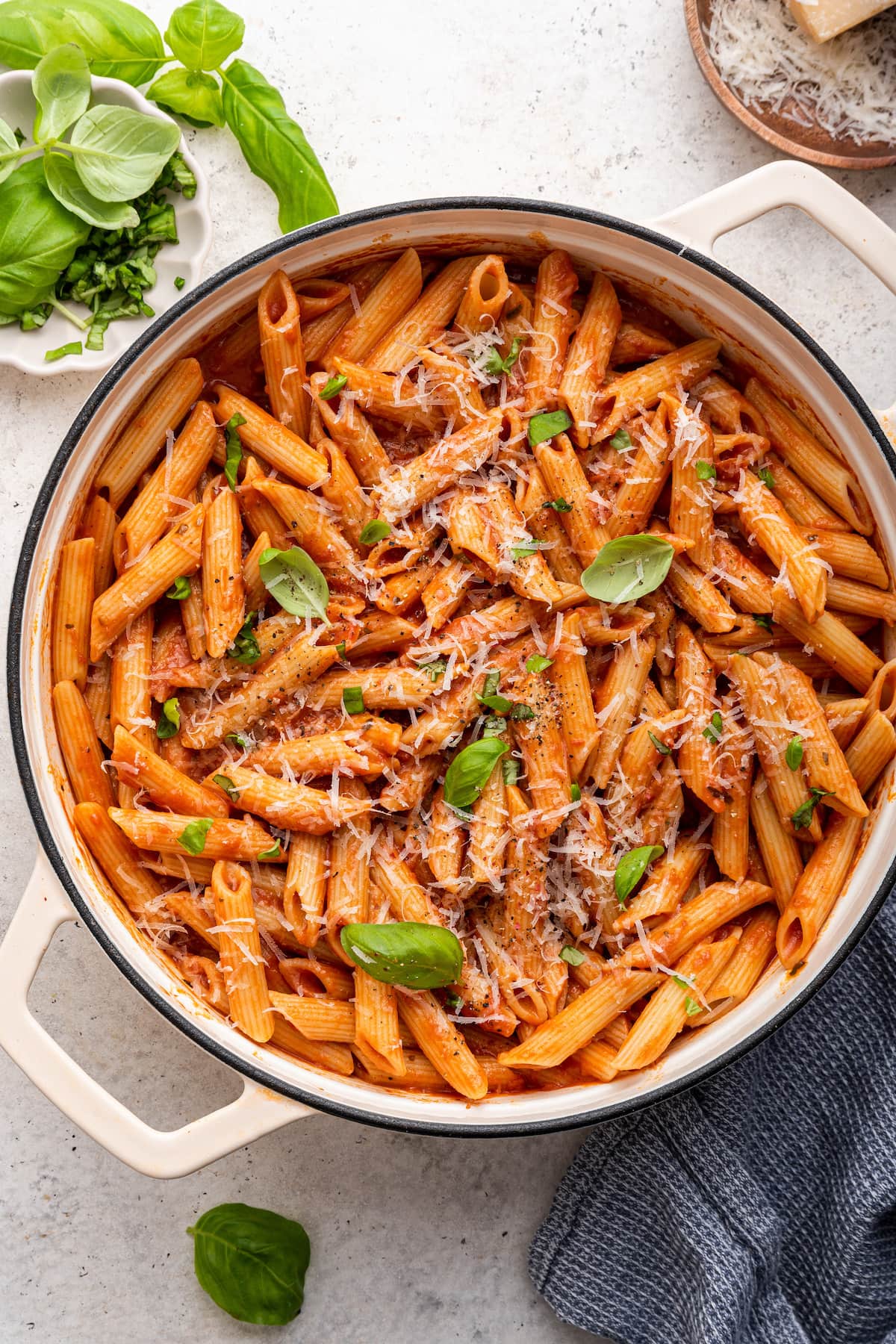 Penne all vodka in a large pot garnished with fresh basil and a dairy-free parmesan.