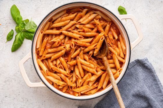 Penne pasta added to the vodka sauce in a large pot.