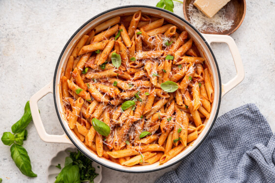 Penne all vodka in a large pot garnished with fresh basil and a dairy-free parmesan.