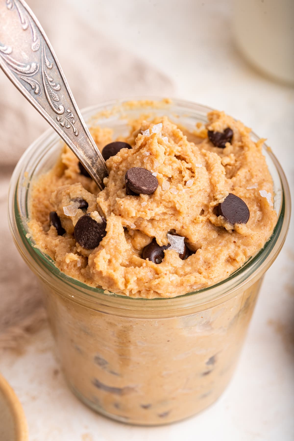 Protein cookie dough in a glass cup with a spoon.