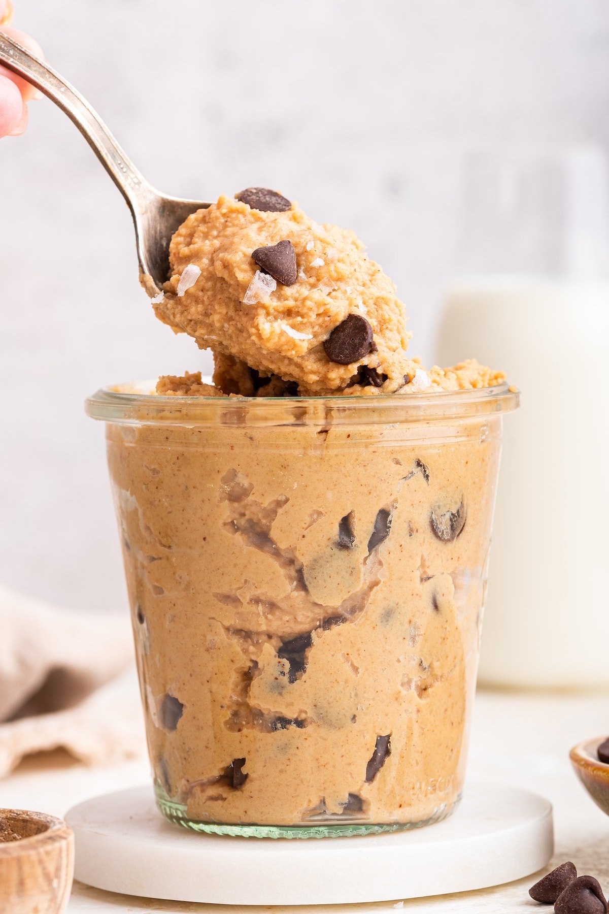 Protein cookie dough in a glass cup with a spoon.