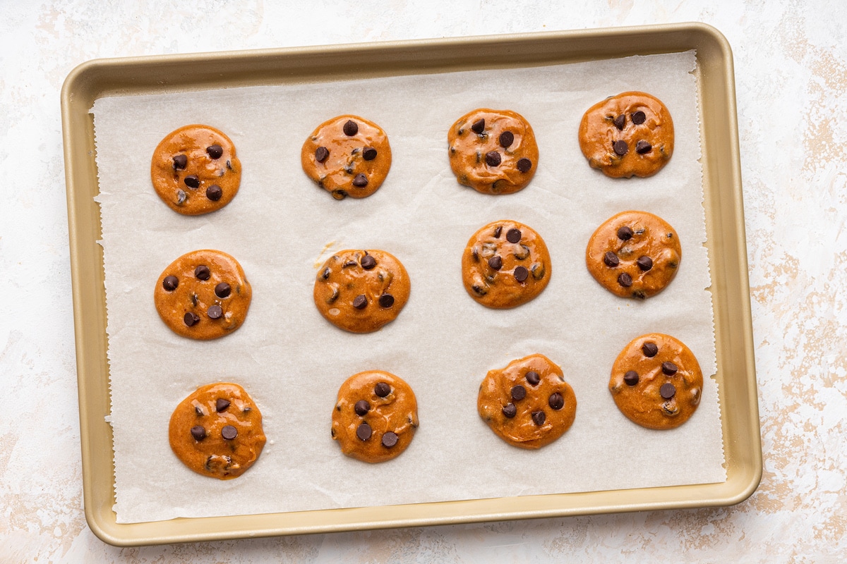 Twelve protein cookies before being baked on a baking tray.