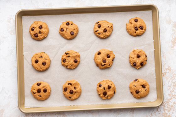 Twelve protein cookies on a baking tray after being baked.