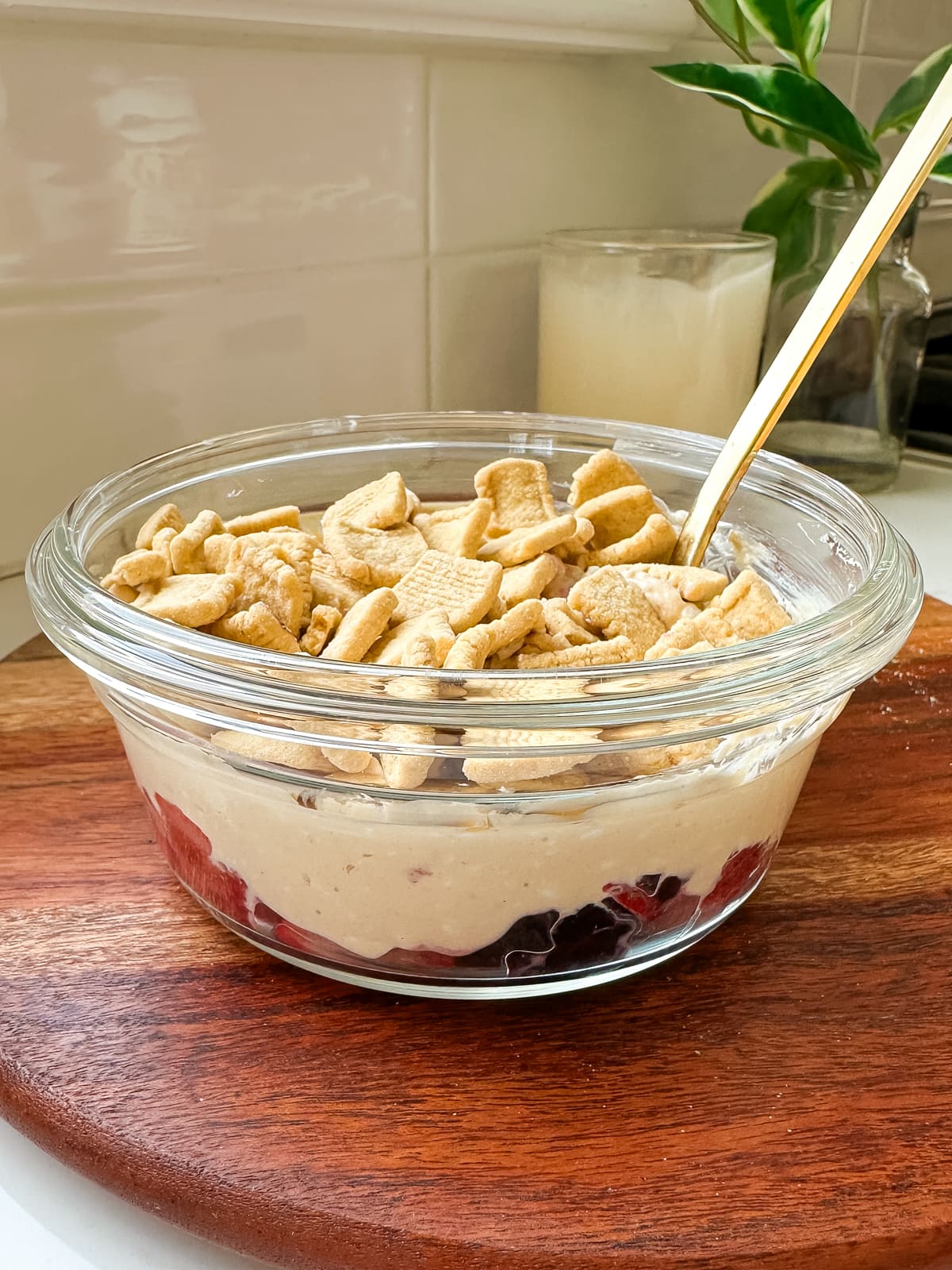 A glass bowl with berries, peanut butter yogurt and Catalina Crunch cereal on top.