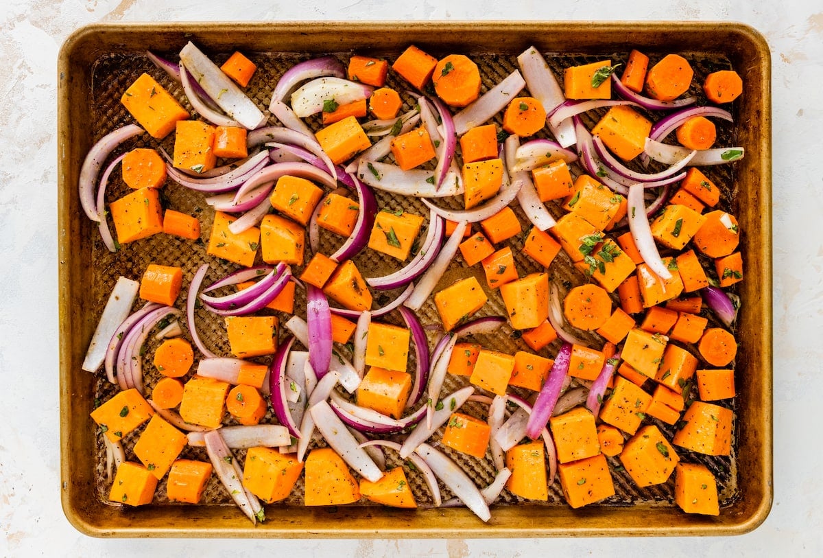 Root vegetables on a baking sheet before being roasted.