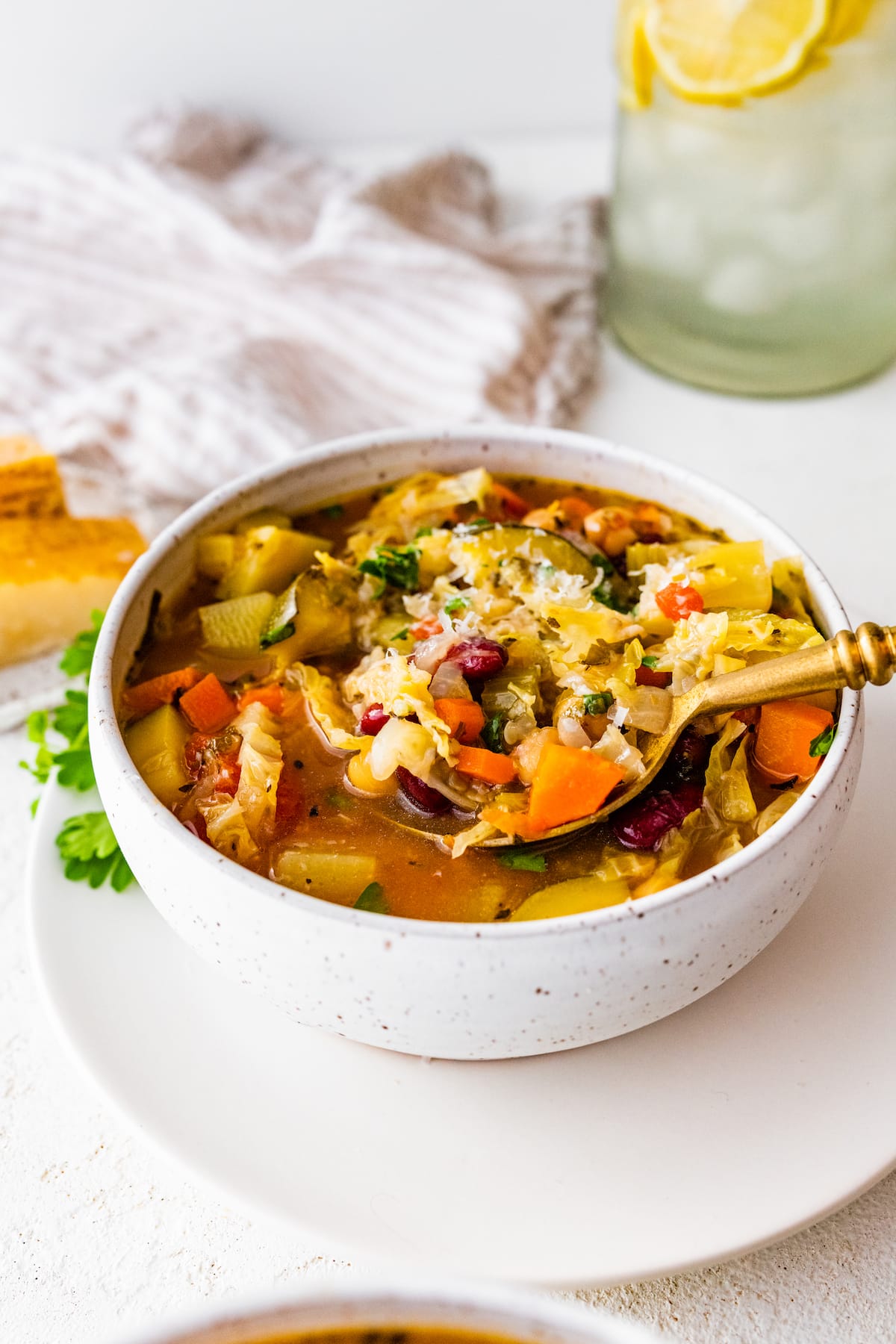 A bowl of minestrone soup with a spoon holding a bite size portion of the soup.