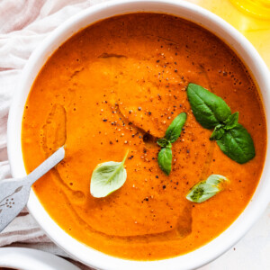 Tomato basil soup garnished with a drizzle of oil and fresh basil in a bowl.