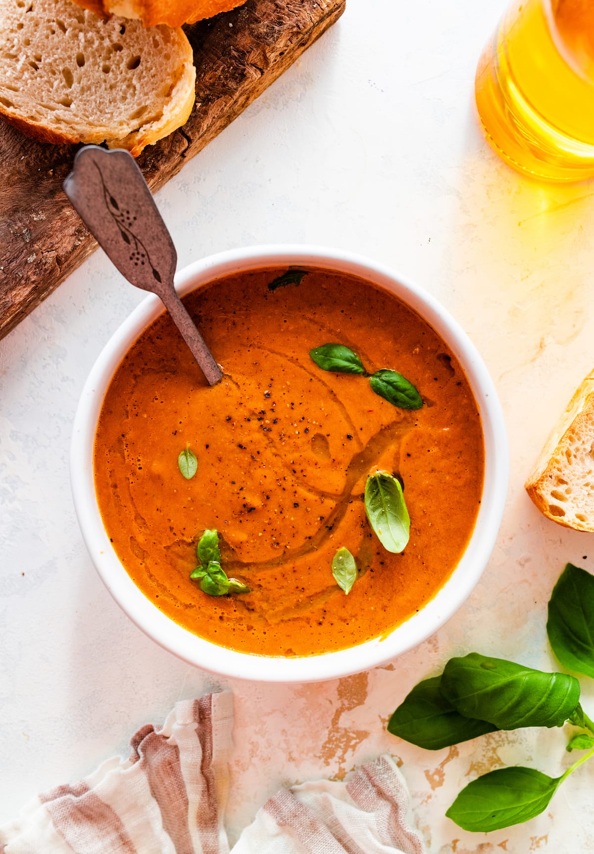 Tomato basil soup garnished with a drizzle of oil and fresh basil in a bowl.