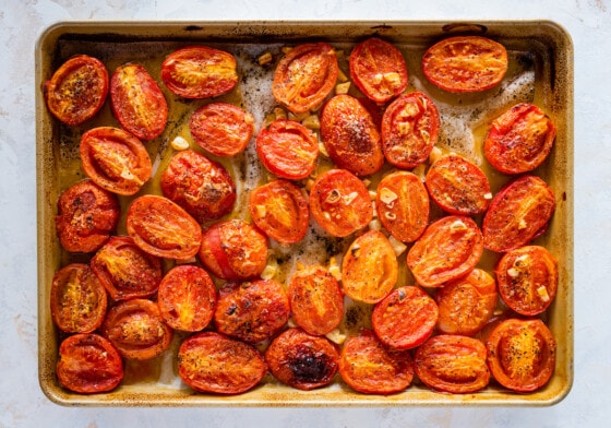 Seasoned halved tomatoes on a baking tray after being roasted.