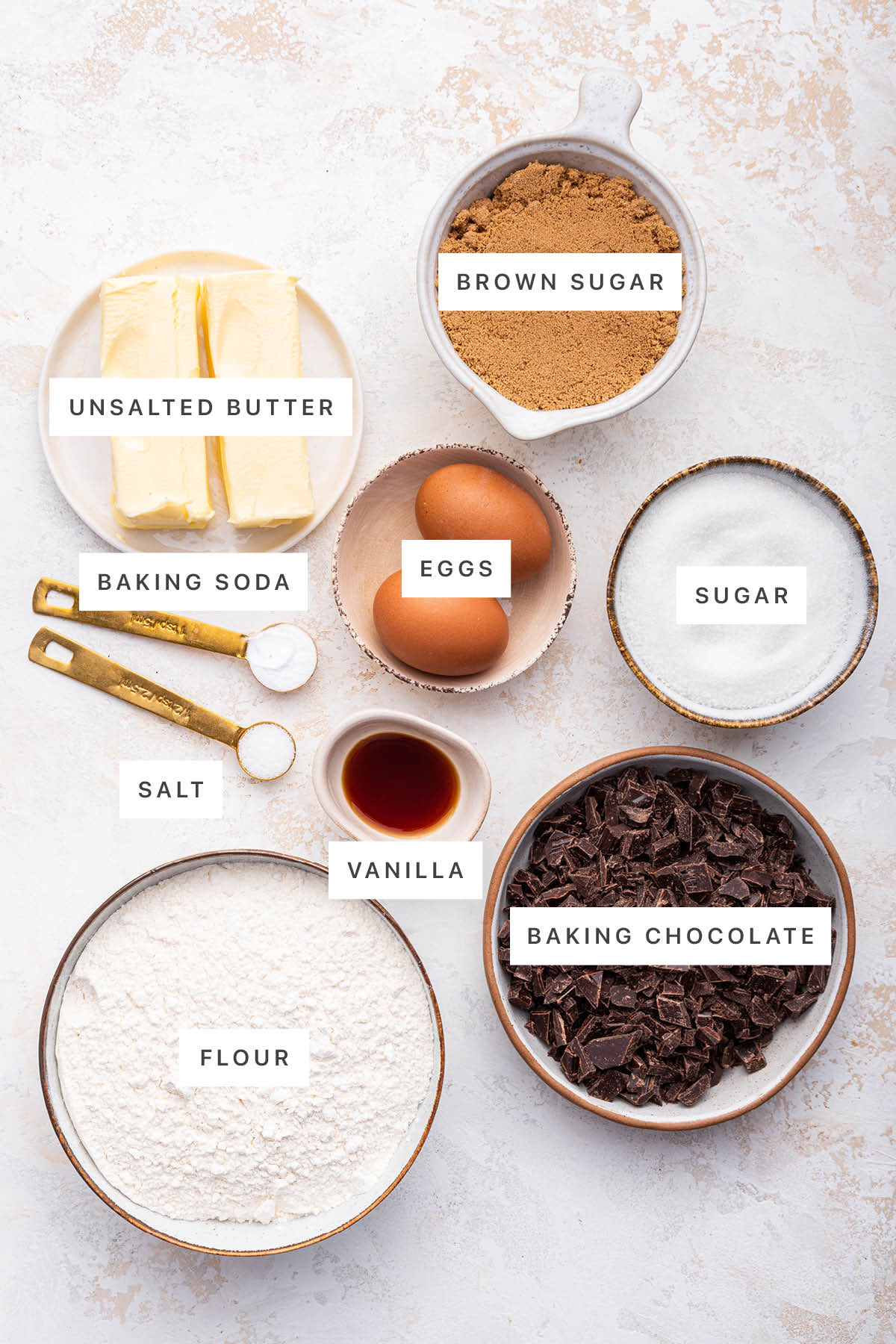 Ingredients measured out to make Brown Butter Chocolate Chip Cookies: unsalted butter, brown sugar, eggs, sugar, baking soda, salt, vanilla, flour and baking chocolate.