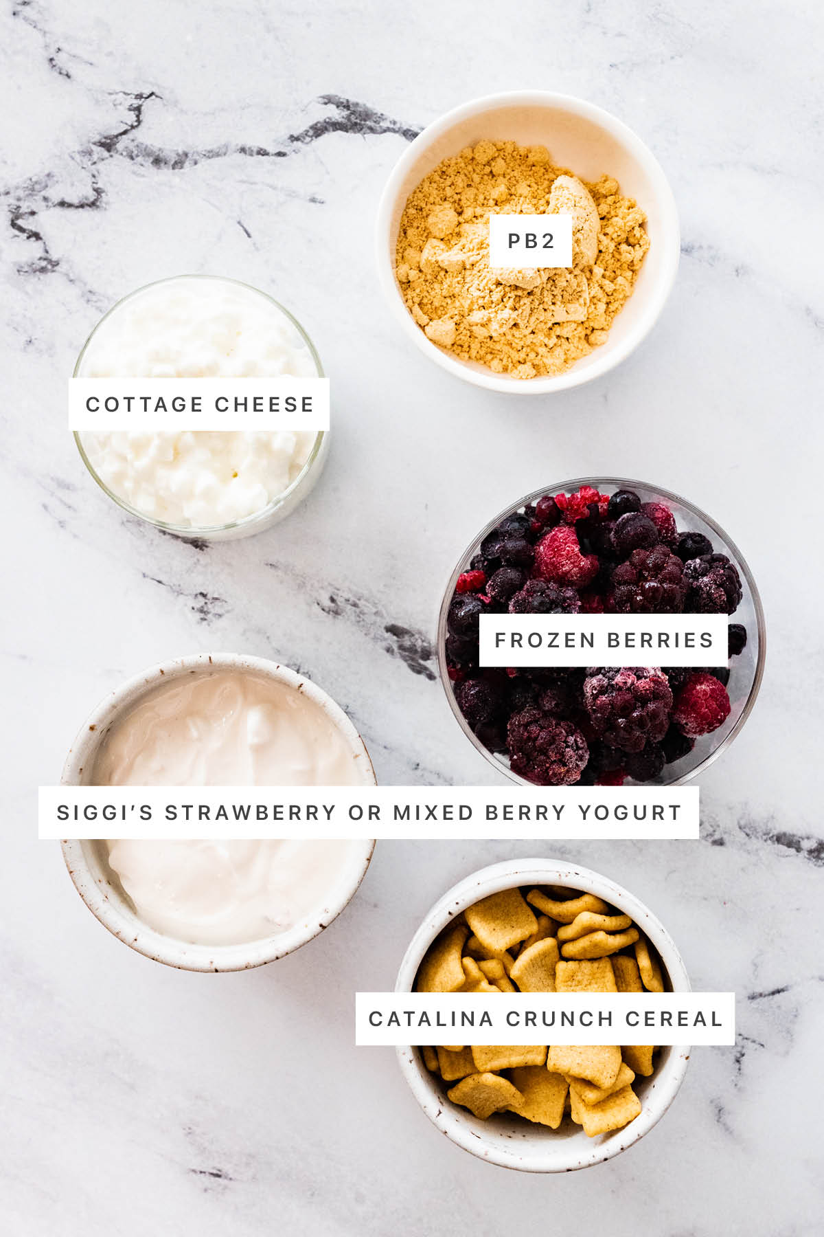 Ingredients measured out to make PB&J Protein Yogurt Bowl: cottage cheese, PB2, frozen berries, Siggi's strawberry yogurt, Catalina Crunch Cereal.