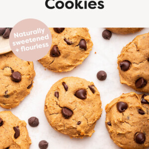 Chocolate chip Protein Cookies on a white table top with some chocolate chips scattered around.