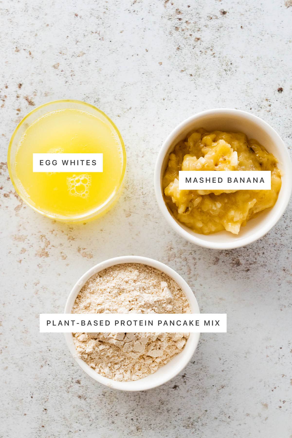 Ingredients measured out to make a Protein Pancake Bowl: egg whites, plant-based protein pancake mix and mashed banana.