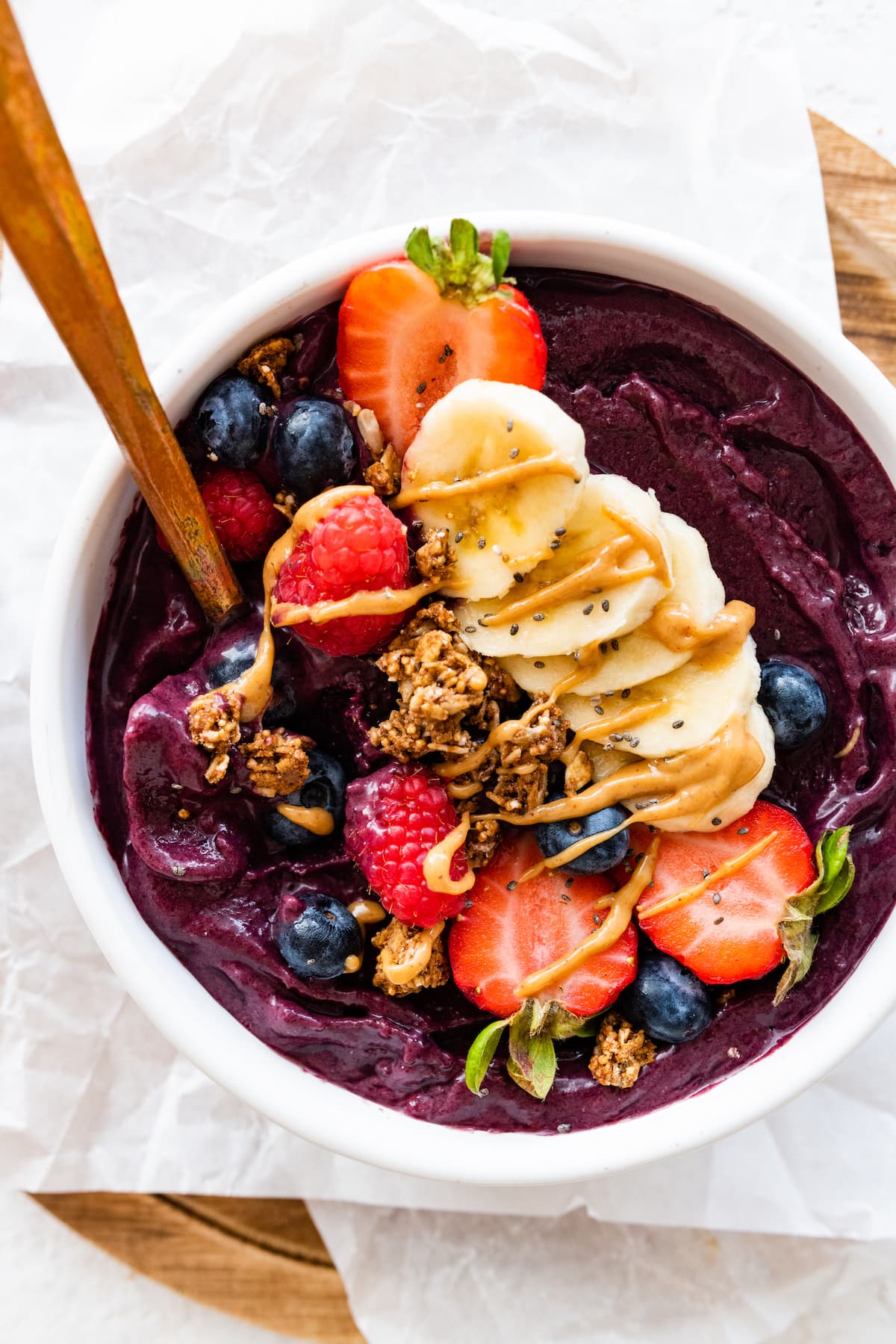 An acai bowl topped with fresh berries, sliced banana, granola, and a drizzle of nut butter.