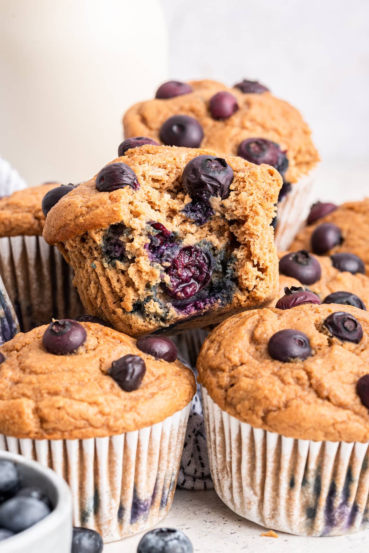 Blueberry protein muffins stacked on one another with one muffin having a large bite taken from it.