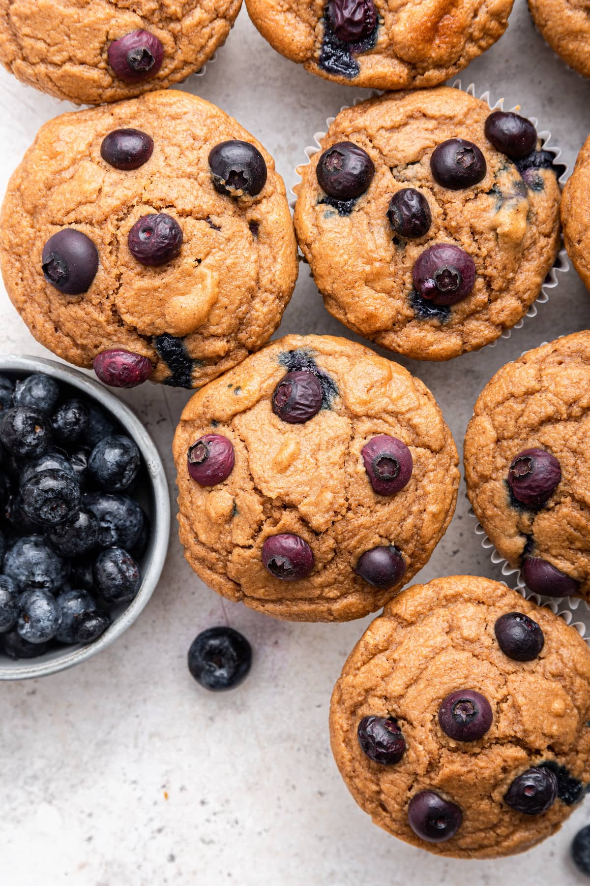 Multiple blueberry protein muffins near one another on a table.