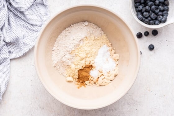 A large mixing bowl of dry ingredients used for blueberry protein muffins.