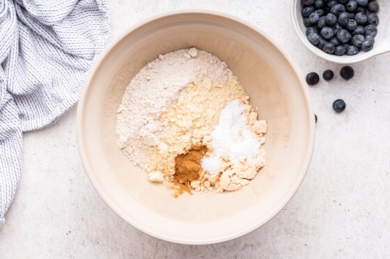 A large mixing bowl of dry ingredients used for blueberry protein muffins.