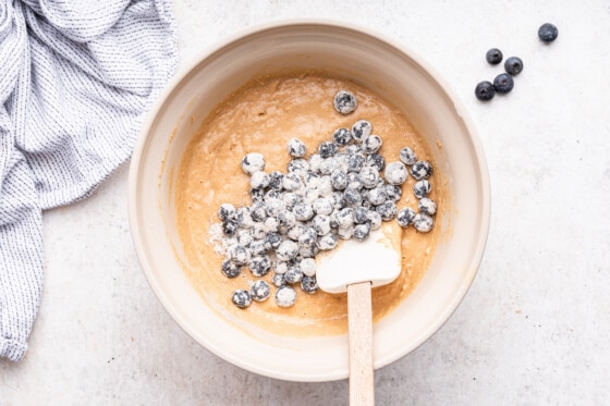 Frozen blueberries added to the batter used to make blueberry protein muffins.