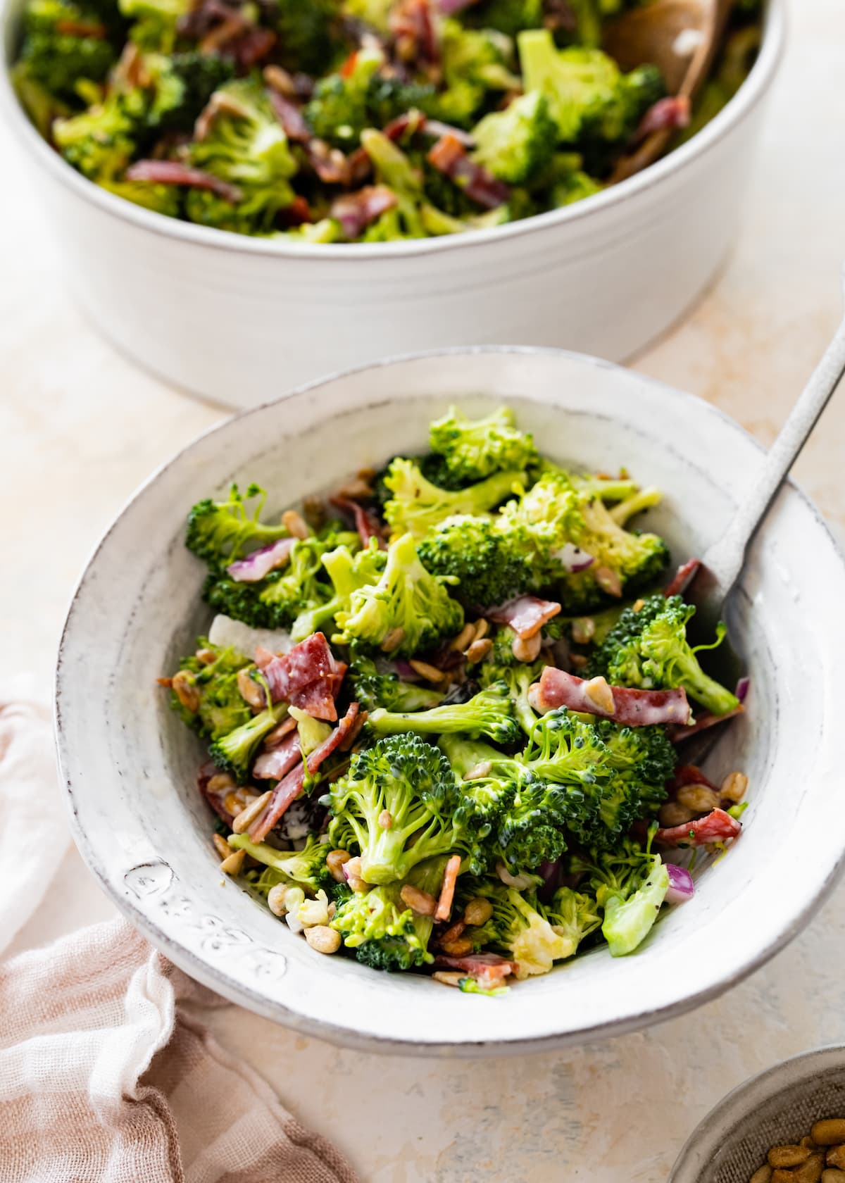 A serving of broccoli salad in a white bowl.