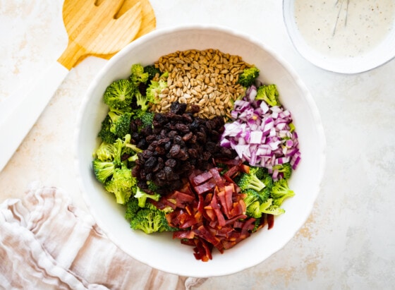 All ingredients for a broccoli salad in a large bowl before being mixed.