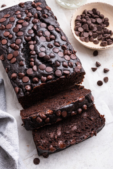 A loaf of chocolate banana bread with two slices cut.