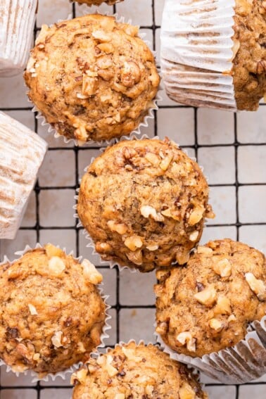 Multiple banana muffins near one another on a cooling rack.