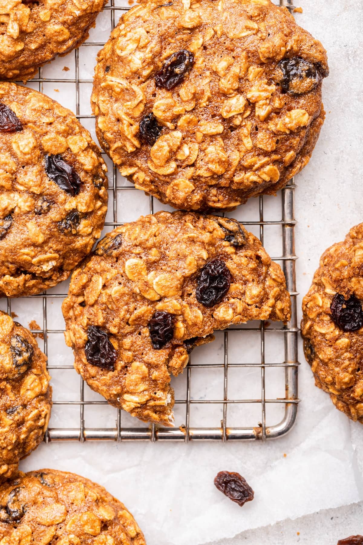 Oatmeal raisin cookies on a cooling rack with one cookie having a bite taken from it.