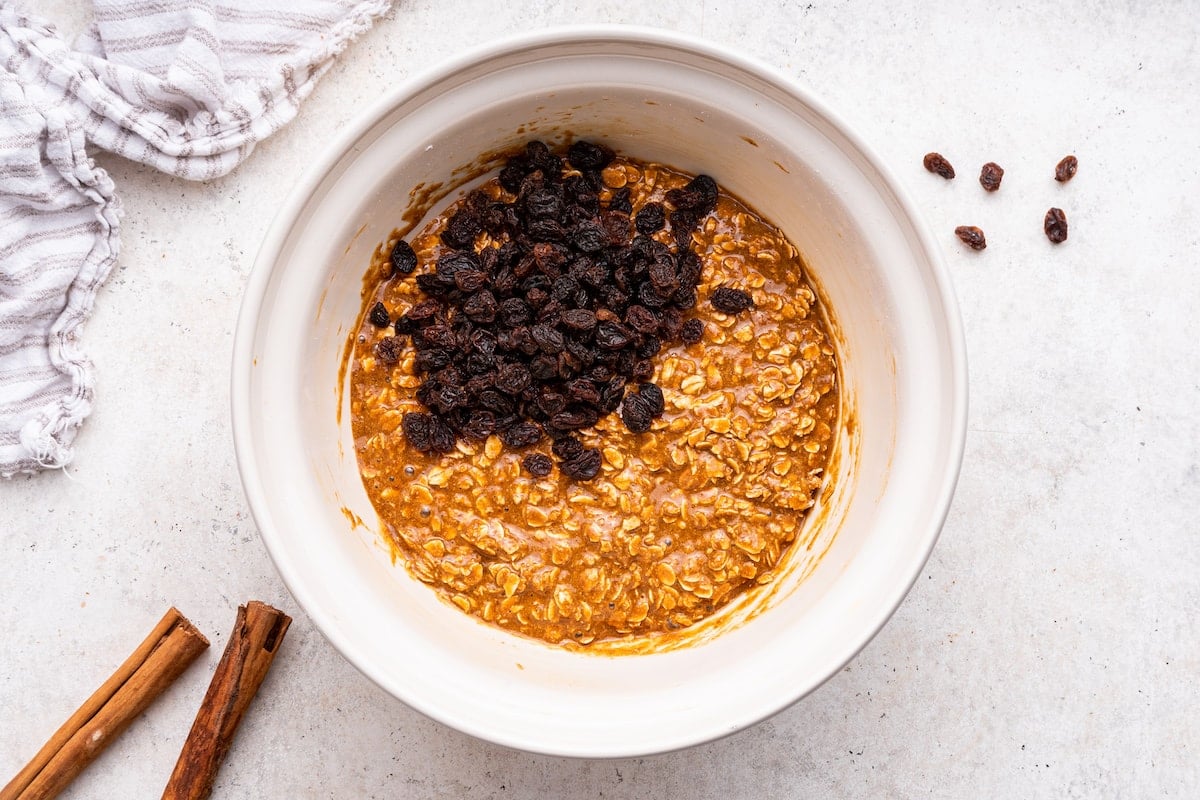 Raisins added to the dough in a large mixing bowl for oatmeal raisin cookies.