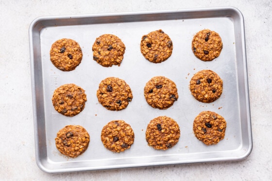Oatmeal raisin cookies on a baking tray after being baked.