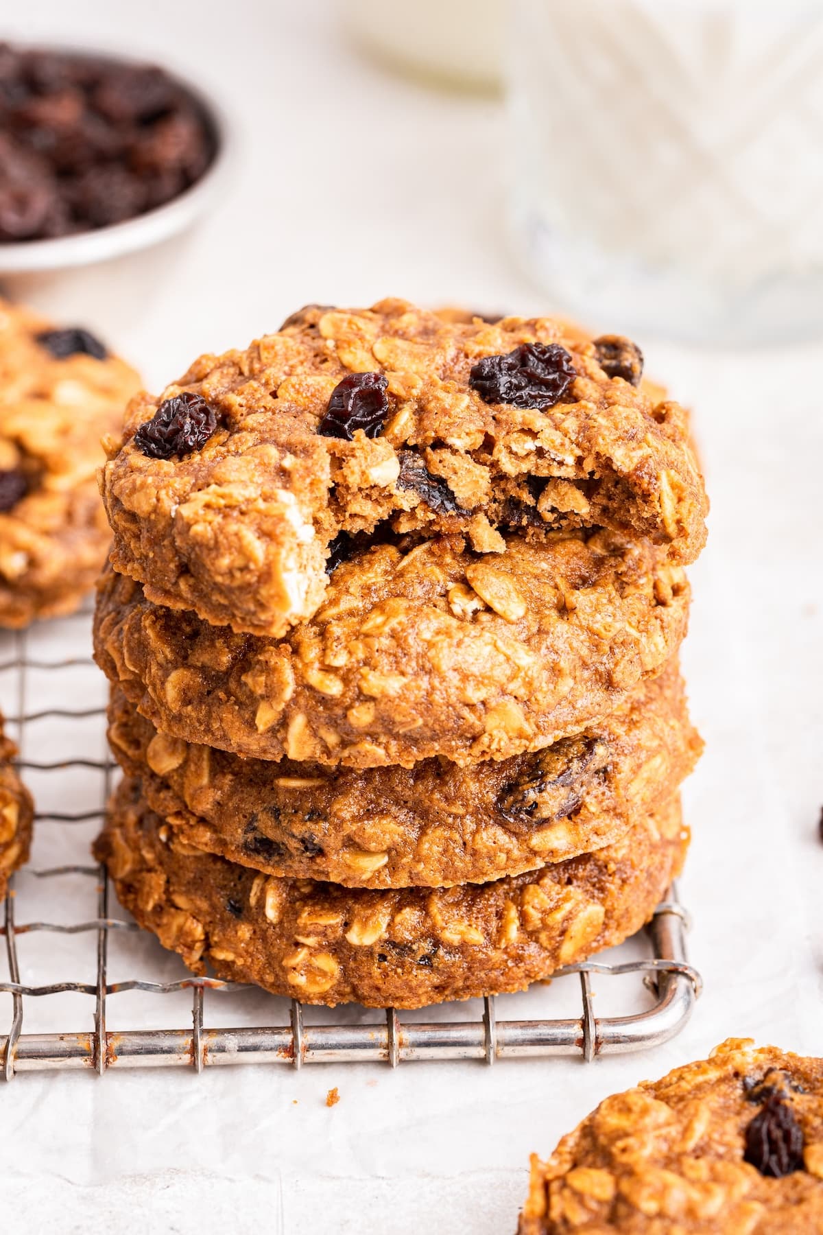 Oatmeal raisin cookies stacked on one another with the top cookie having a bite taken from it.