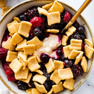 A peanut butter and jelly yogurt bowl topped with crunchy cereal and fresh berries.