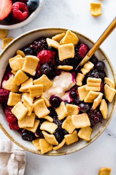 A peanut butter and jelly yogurt bowl topped with crunchy cereal and fresh berries.