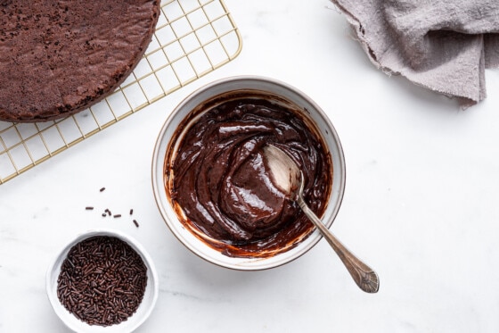A chocolate frosting in a small bowl with a spoon.