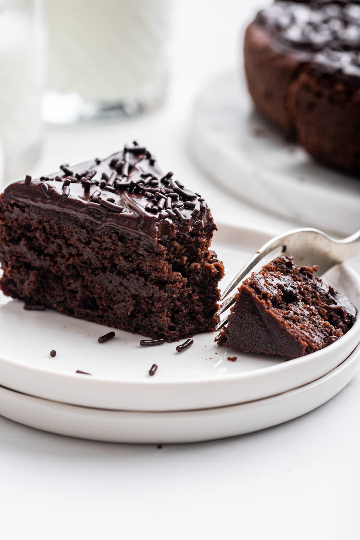 A small bite-sized portion taken from a slice of chocolate protein cake with a fork.