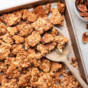 Protein granola on a baking tray with a wooden serving spoon.