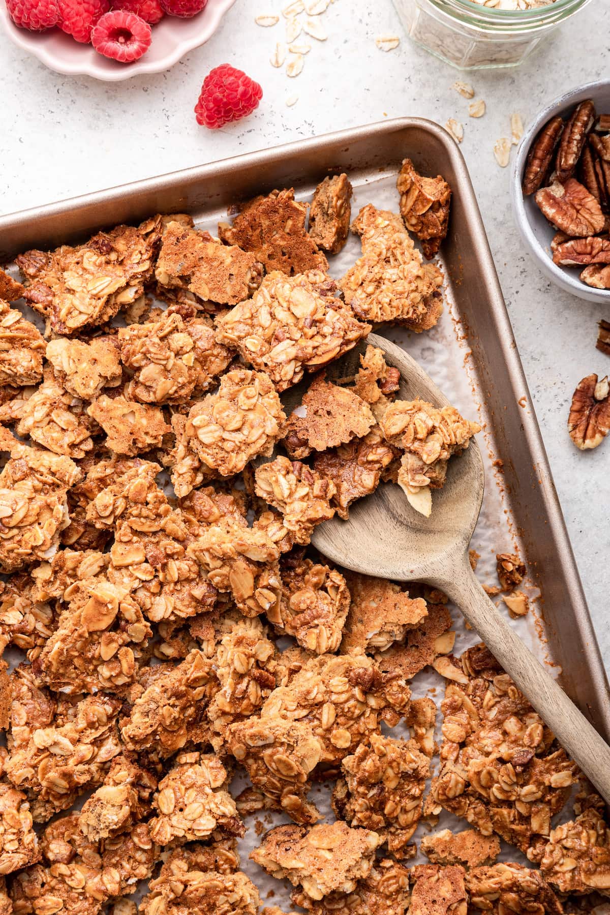 Protein granola on a baking tray with a wooden serving spoon.