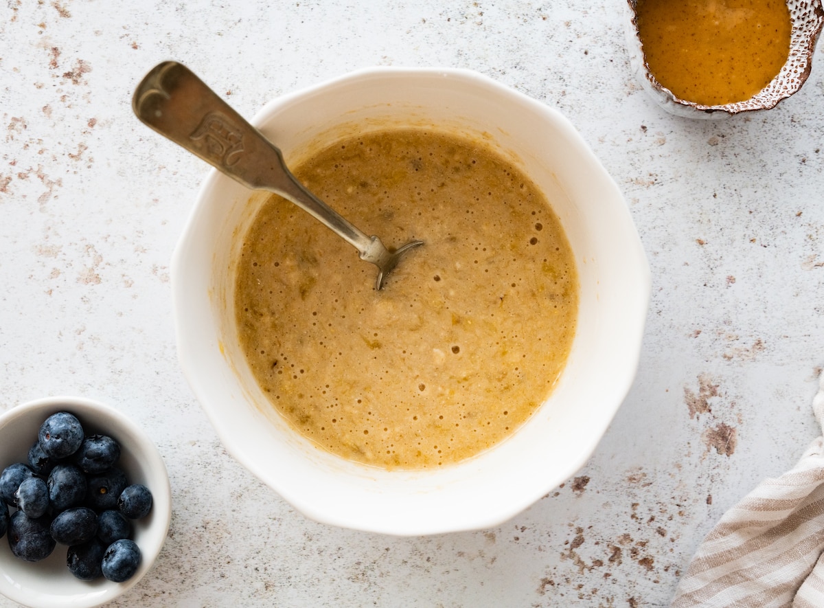 All ingredients used for a protein pancake in a mixing bowl with a spoon.