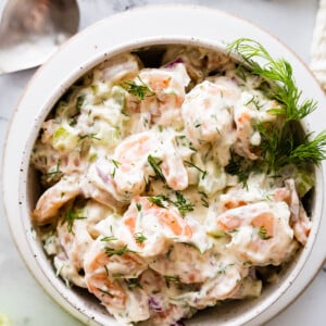 Shrimp salad in a serving bowl topped with fresh dill.