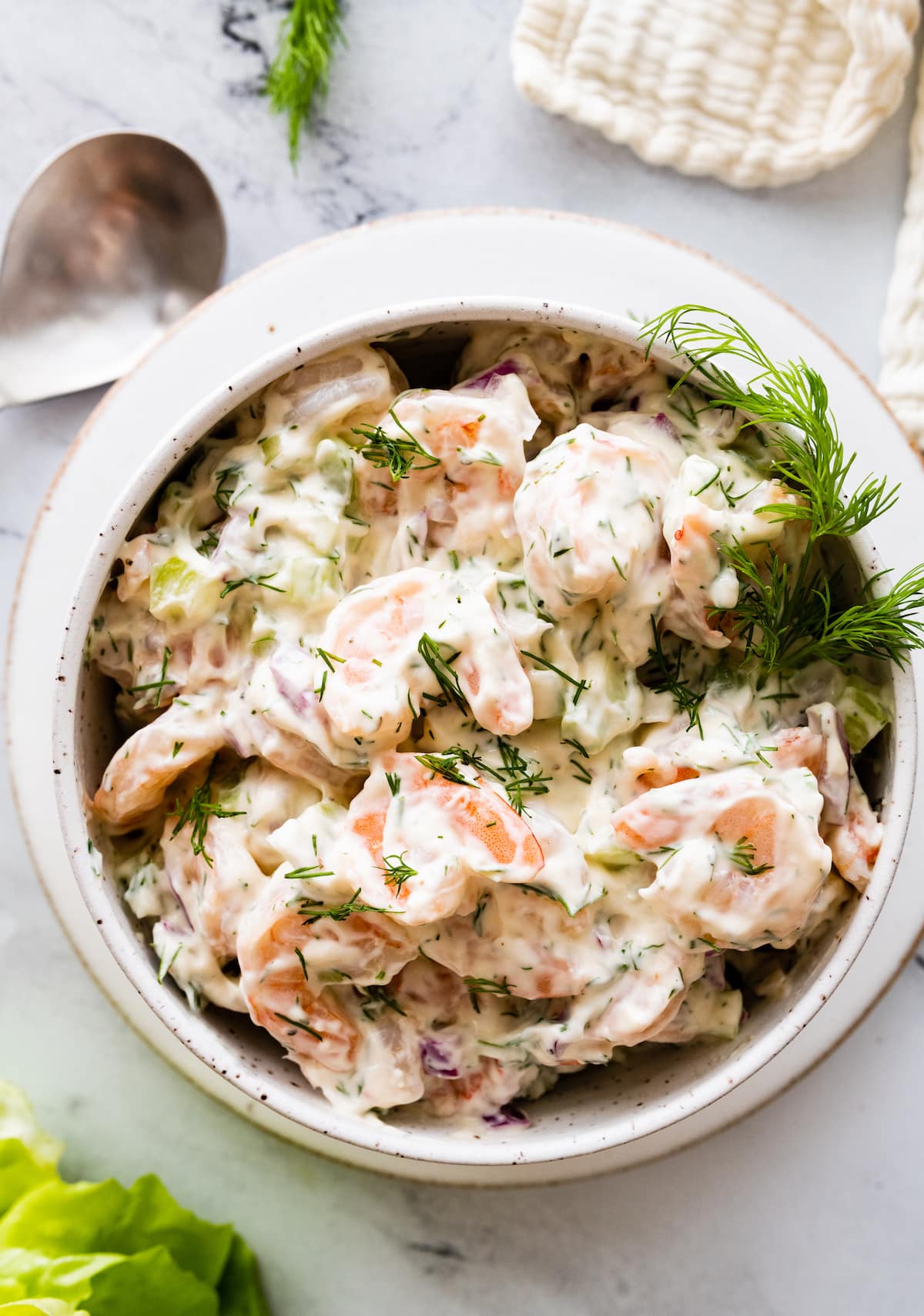 Shrimp salad in a serving bowl topped with fresh dill.